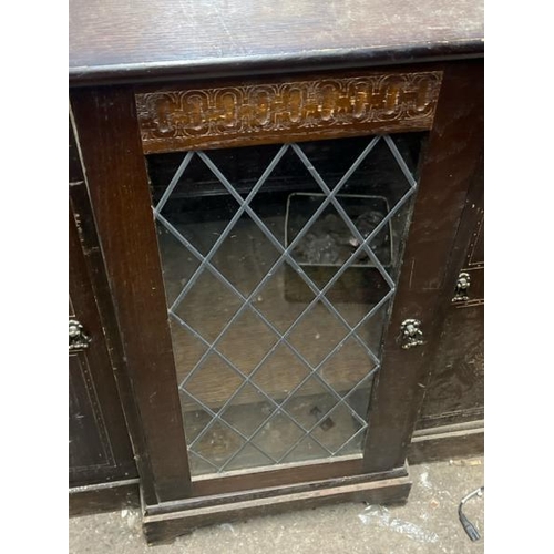 15 - An oak cupboard with carved side panels and glass display centrepiece, not including internal conten... 