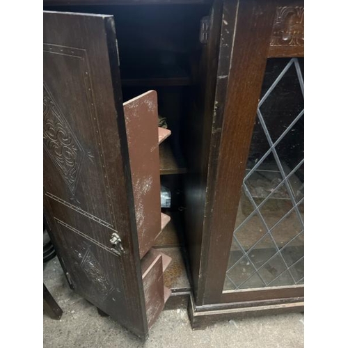 15 - An oak cupboard with carved side panels and glass display centrepiece, not including internal conten... 