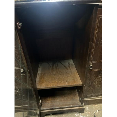 15 - An oak cupboard with carved side panels and glass display centrepiece, not including internal conten... 