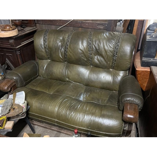 21 - An oak coffee table and two seater green leather sofa set, with riveted, carved and leather-bound fe... 