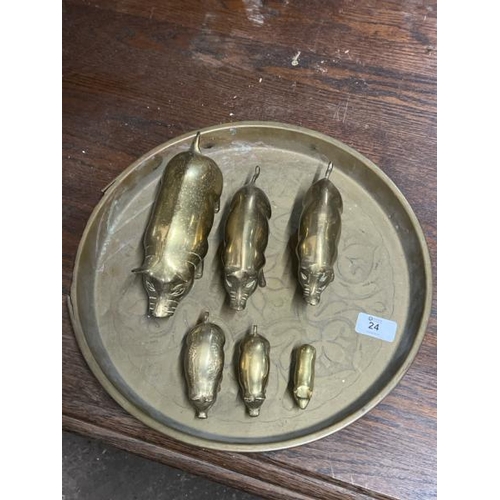 24 - A family of six brass pigs and charger, largest 20cm long, charger 35cm in diameter