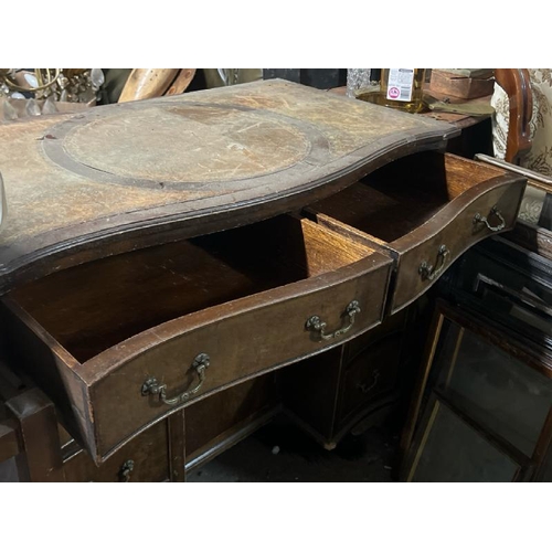 31 - A bow fronted oak desk with leather top inlay, 77cm high x 91cm wide x 52cm deep