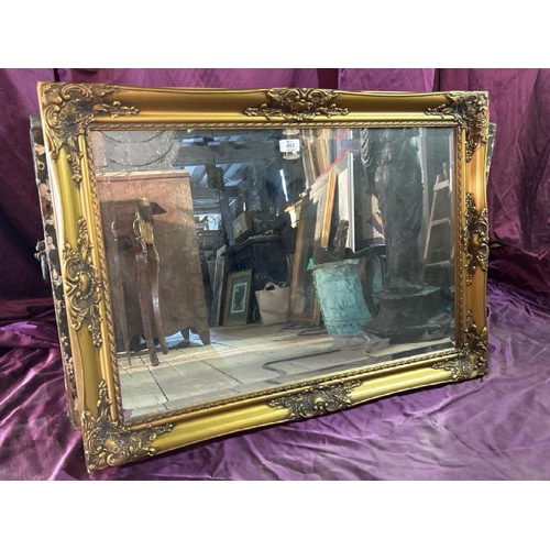 493 - An elegant 20th century wall mirror with beviled edging and profusely gilted frame, 65cm (h) x 89cm ... 