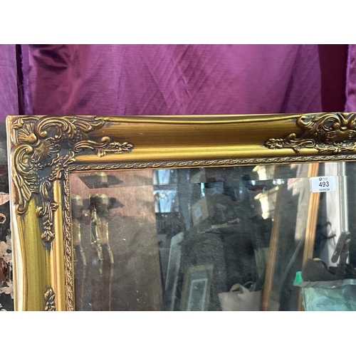 493 - An elegant 20th century wall mirror with beviled edging and profusely gilted frame, 65cm (h) x 89cm ... 