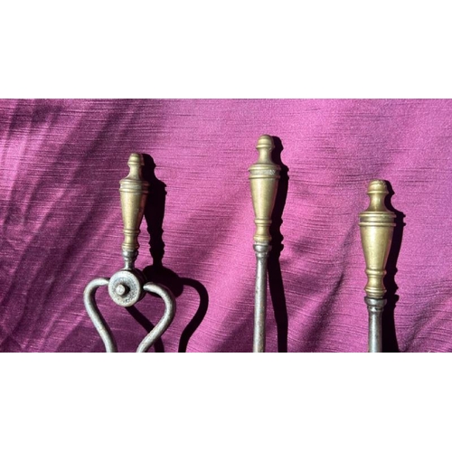 533 - A set of three metal fire tools with brass finials  / All lots are located at The Barn, Hampstead Fa... 