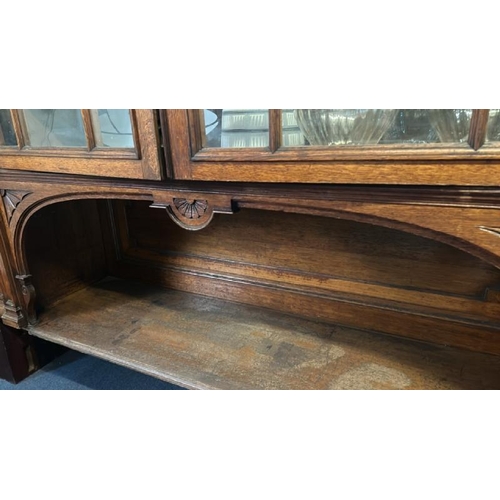 26 - An Edwardian oak top section of a dresser with ornately carved paneling and glazed features, on unas... 