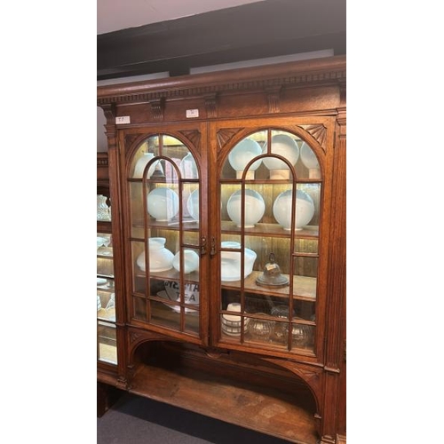 26 - An Edwardian oak top section of a dresser with ornately carved paneling and glazed features, on unas... 