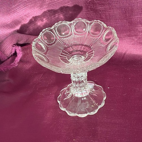 748 - Vintage glass compote with scalloped edge and intricate raised pattern. It is clear glass and stands... 