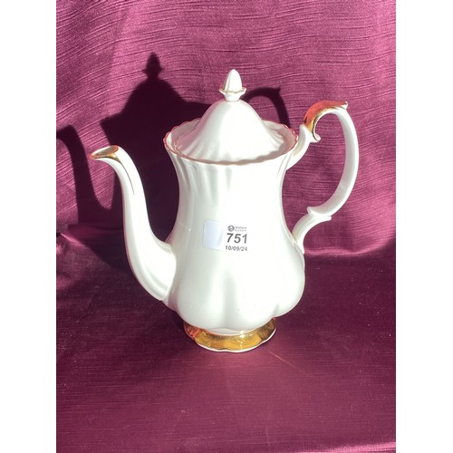 751 - A porcelain teapot with a scalloped design. There are gold accents on the spout, handle, and base. T... 