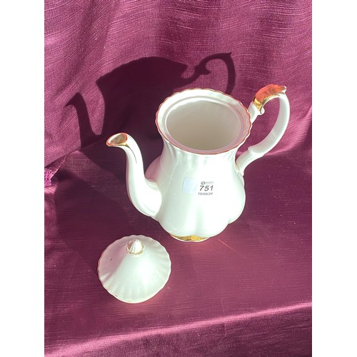 751 - A porcelain teapot with a scalloped design. There are gold accents on the spout, handle, and base. T... 