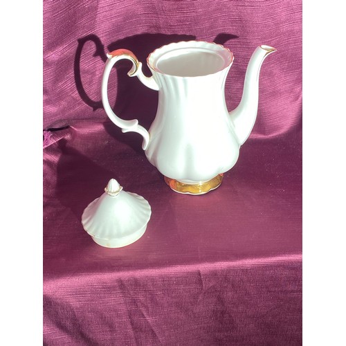 751 - A porcelain teapot with a scalloped design. There are gold accents on the spout, handle, and base. T... 