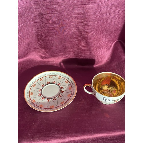 756 - A porcelain teacup and saucer featuring intricate red and gold geometric patterns. The interior of t... 