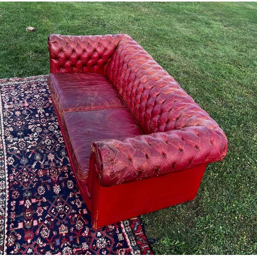 694 - A 20th century fully buttoned Chesterfield sofa in rich red leather hyde, repaired damage to one arm... 