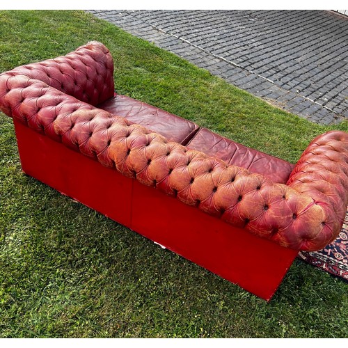 694 - A 20th century fully buttoned Chesterfield sofa in rich red leather hyde, repaired damage to one arm... 