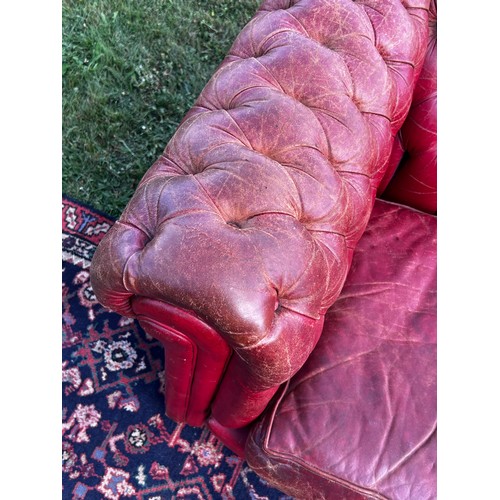 694 - A 20th century fully buttoned Chesterfield sofa in rich red leather hyde, repaired damage to one arm... 