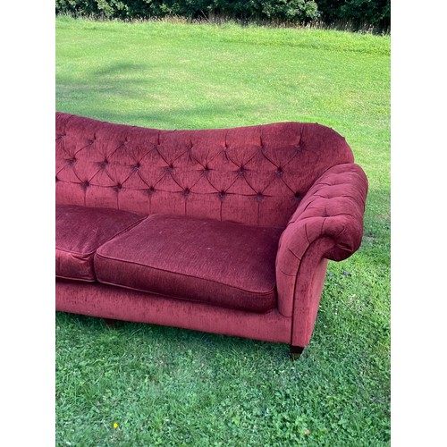 695 - A deep red buttoned Chesterfield sofa with scroll over arms and humped back, good classic style, in ... 