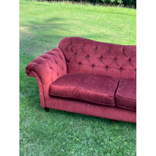 695 - A deep red buttoned Chesterfield sofa with scroll over arms and humped back, good classic style, in ... 