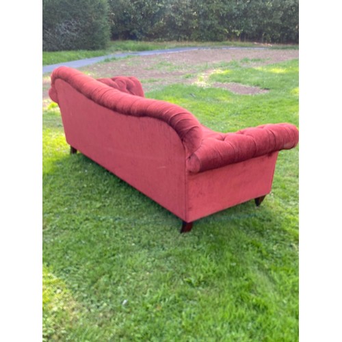 695 - A deep red buttoned Chesterfield sofa with scroll over arms and humped back, good classic style, in ... 