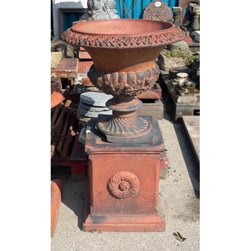 687 - A large and ornate terracotta urn on plinth, with finely detailed roll top edging and floral motif o... 