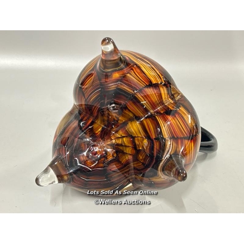 19 - A large heavy Murano style glass jug with amber, black and red tones on three legs, 23 cm high / T43