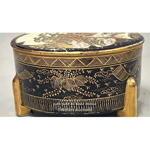 13 - A Japanese Satsuma three footed box with cover, gilt decoration on blue ground. Cover depicting a vi... 