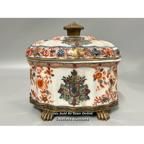 33 - French Samson style porcelain box and cover on brass paw stand, decorated with a pseudo coat of arms... 