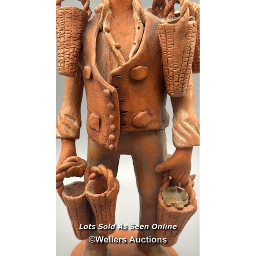 156 - A clay figurine of a man holding baskets, indistinctly signed 23cm high and a vintage West German Wo... 