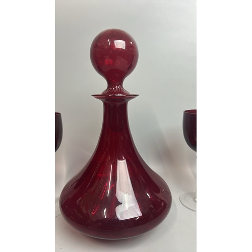 41 - A large red glass / cranberry decanter / bottle with four red and clear stemmed wine glasses, decant... 