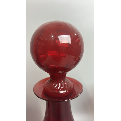 41 - A large red glass / cranberry decanter / bottle with four red and clear stemmed wine glasses, decant... 