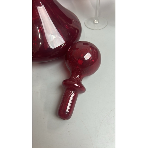 41 - A large red glass / cranberry decanter / bottle with four red and clear stemmed wine glasses, decant... 