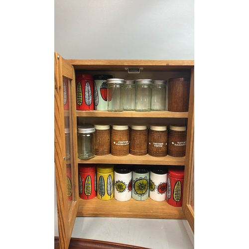 37 - Small spice cupboard with assorted spice pots, wooden serving tray and decorative plates / T15