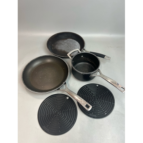 65 - Two Les Creuset frying pans and saucepan with two rubber mats / T29