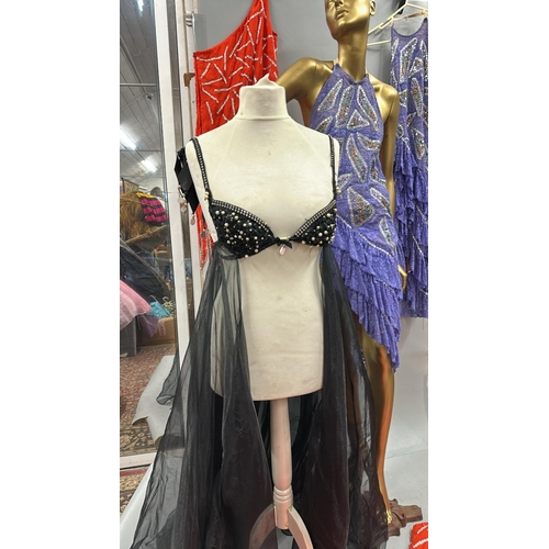 63 - Assorted stage worn garments including two purple frilly dresses, a black sequined bra top with shee... 