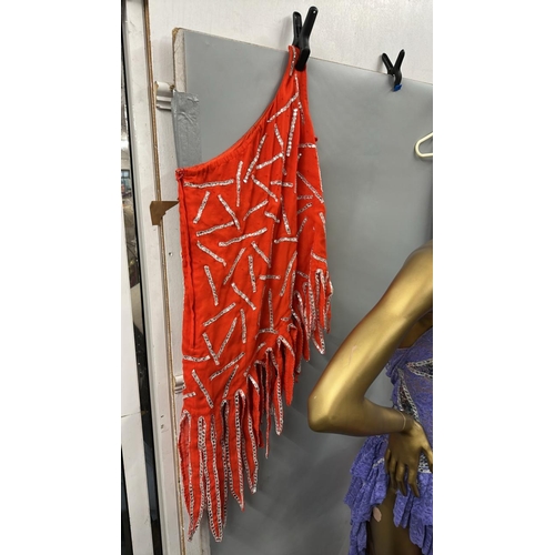 63 - Assorted stage worn garments including two purple frilly dresses, a black sequined bra top with shee... 