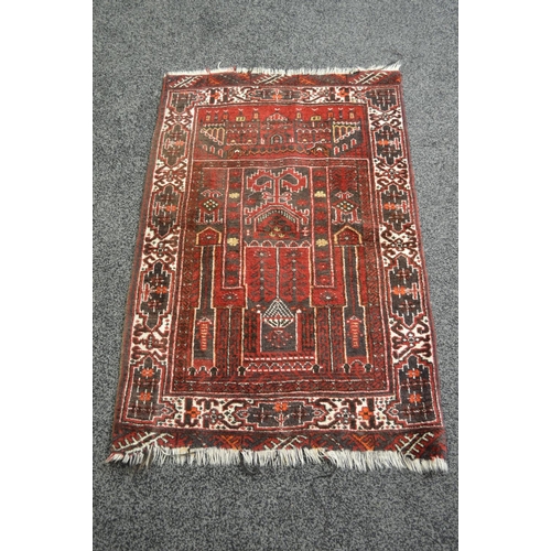 22 - Red ground rug having black, white and beige decoration with end tassels - 55'' x 35''