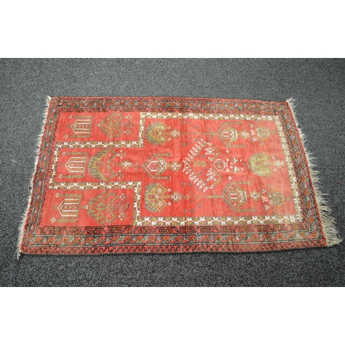 27 - Red ground rug having black, white and beige decoration with end tassels - 58'' x 37.75''