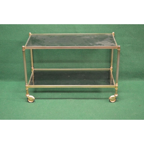 42 - Brass and glass two tier trolley the top having smoked glass supported on reeded brass uprights lead... 