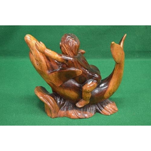 157 - Hardwood carved figure of a young child riding on the belly of a Dolphin, standing on a carved woode... 