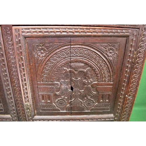 22 - Period oak buffet/court cupboard the top having heavily carved decoration with two panelled doors on... 