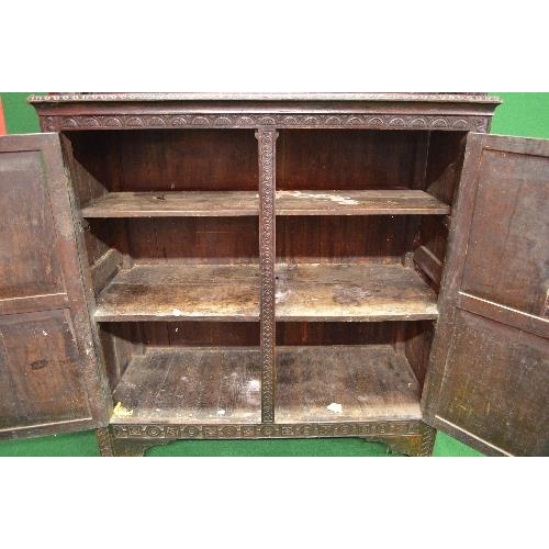 22 - Period oak buffet/court cupboard the top having heavily carved decoration with two panelled doors on... 