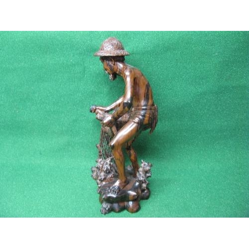 281 - Hardwood carved figure of a fisherman pulling his nets and catch from the water - 19.75