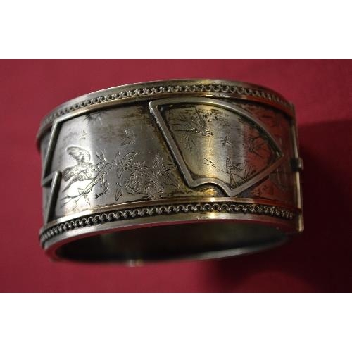 351 - Victorian oval hinged bangle, the front decorated with birds, a bat and sprays, in the Aesthetic Mov... 