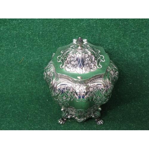 396 - Ornately embossed silver tea caddy having hinged lid, standing on four lions paw feet