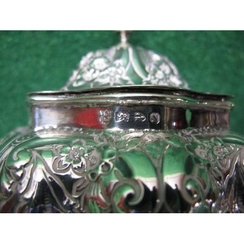 396 - Ornately embossed silver tea caddy having hinged lid, standing on four lions paw feet