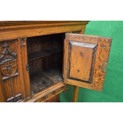 122 - Oak carved side cabinet having single panelled door carved with decoration of a figure opening to re... 