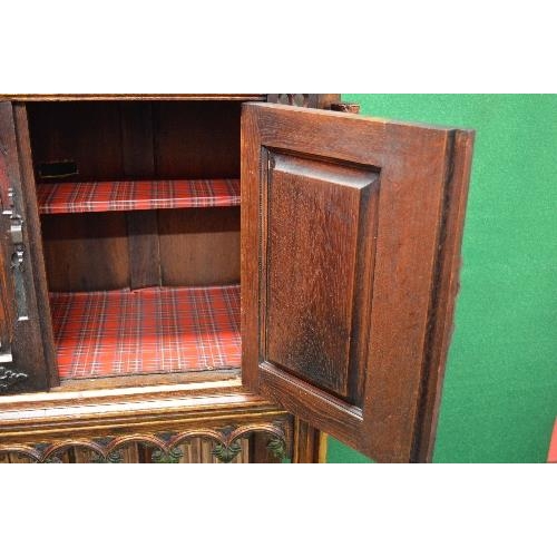 33 - Oak carved side cabinet having cut corners the top having two panelled doors decorated with carved p... 