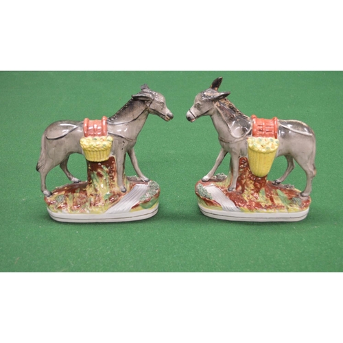 330 - Pair of Staffordshire figures of donkeys carrying vegetables, standing on oval bases - 9.25