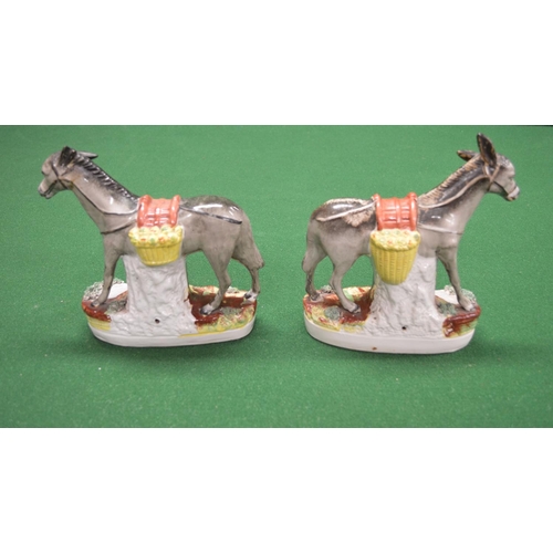 330 - Pair of Staffordshire figures of donkeys carrying vegetables, standing on oval bases - 9.25