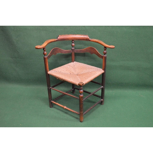 55 - Early 19th century elm corner chair having scrolled arms and shaped back rails, the rush seat being ... 