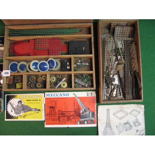 229 - Two wooden boxes of assorted Meccano parts including wheels, gears, two clockwork motors etc